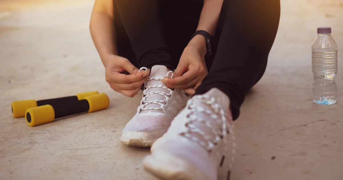 Amateur athlete lacing up running shoes at home before a workout