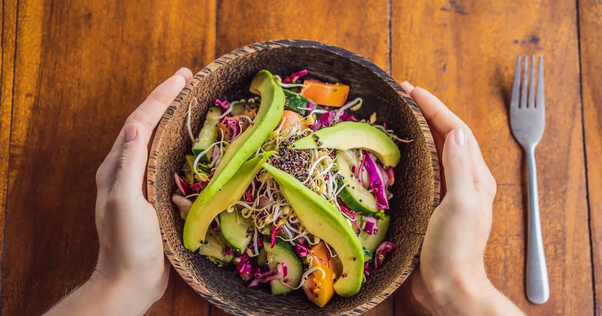 A quinoa bowl with salmon, cucumber and avocado on a wooden table in natural light