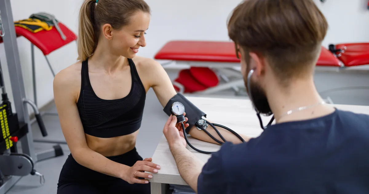 Athlete in training clothes undergoing a cardiac stress test with a cardiologist at a clinic